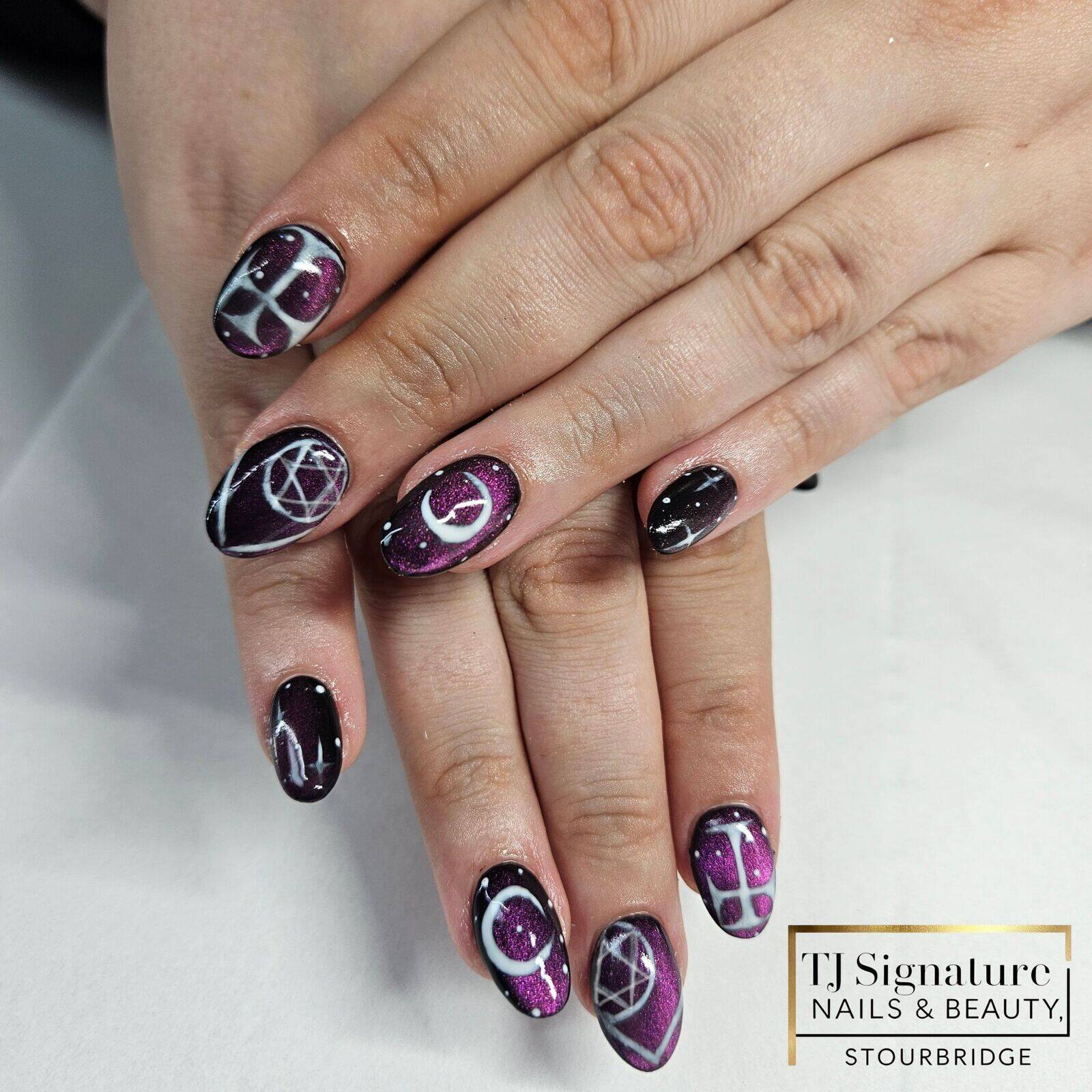 Mystical purple cat-eye acrylic nails featuring celestial and geometric white line designs – a bold, cosmic-inspired look perfect for making a statement.
