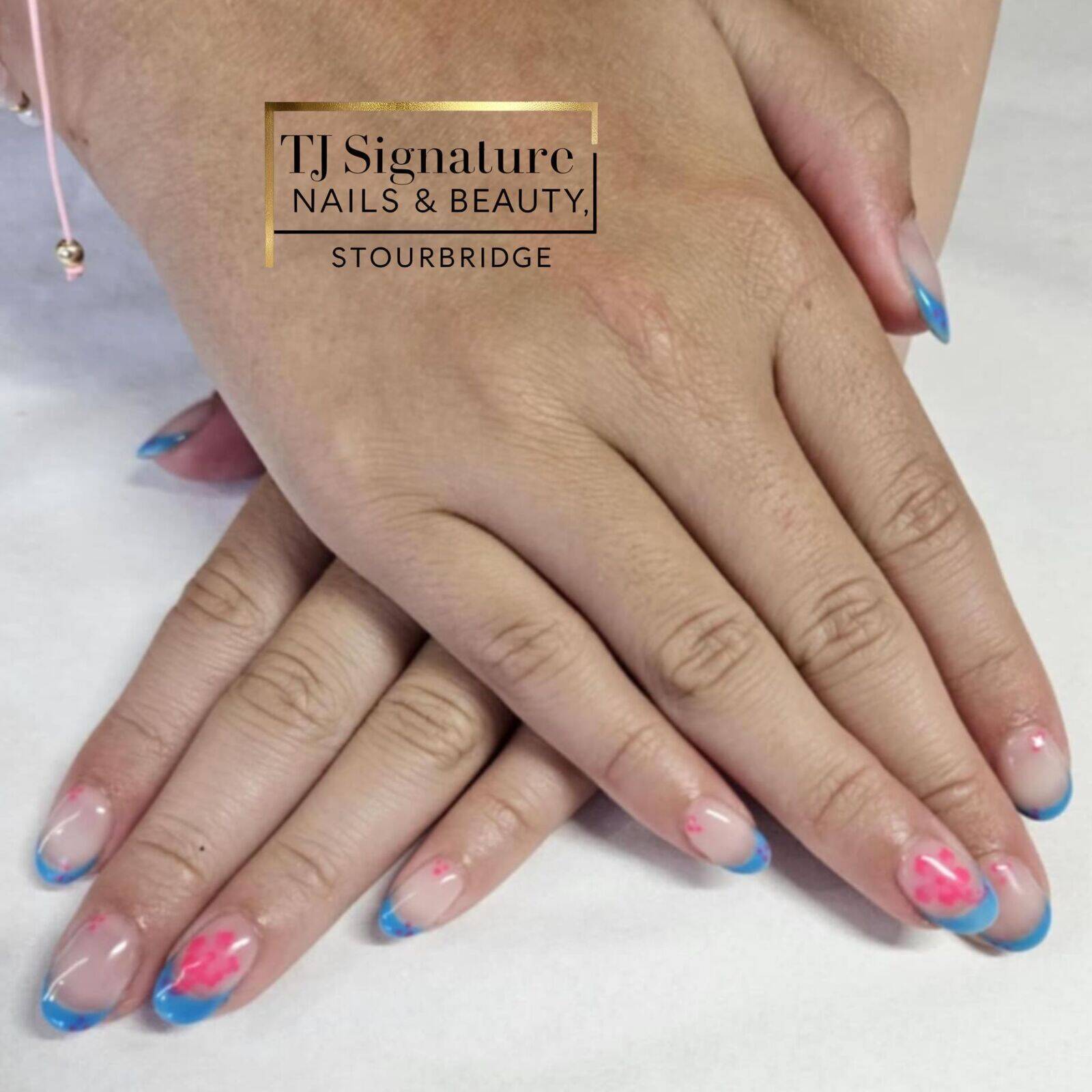 Bright blue French tips with playful pink floral accents. Gel over natural nails.