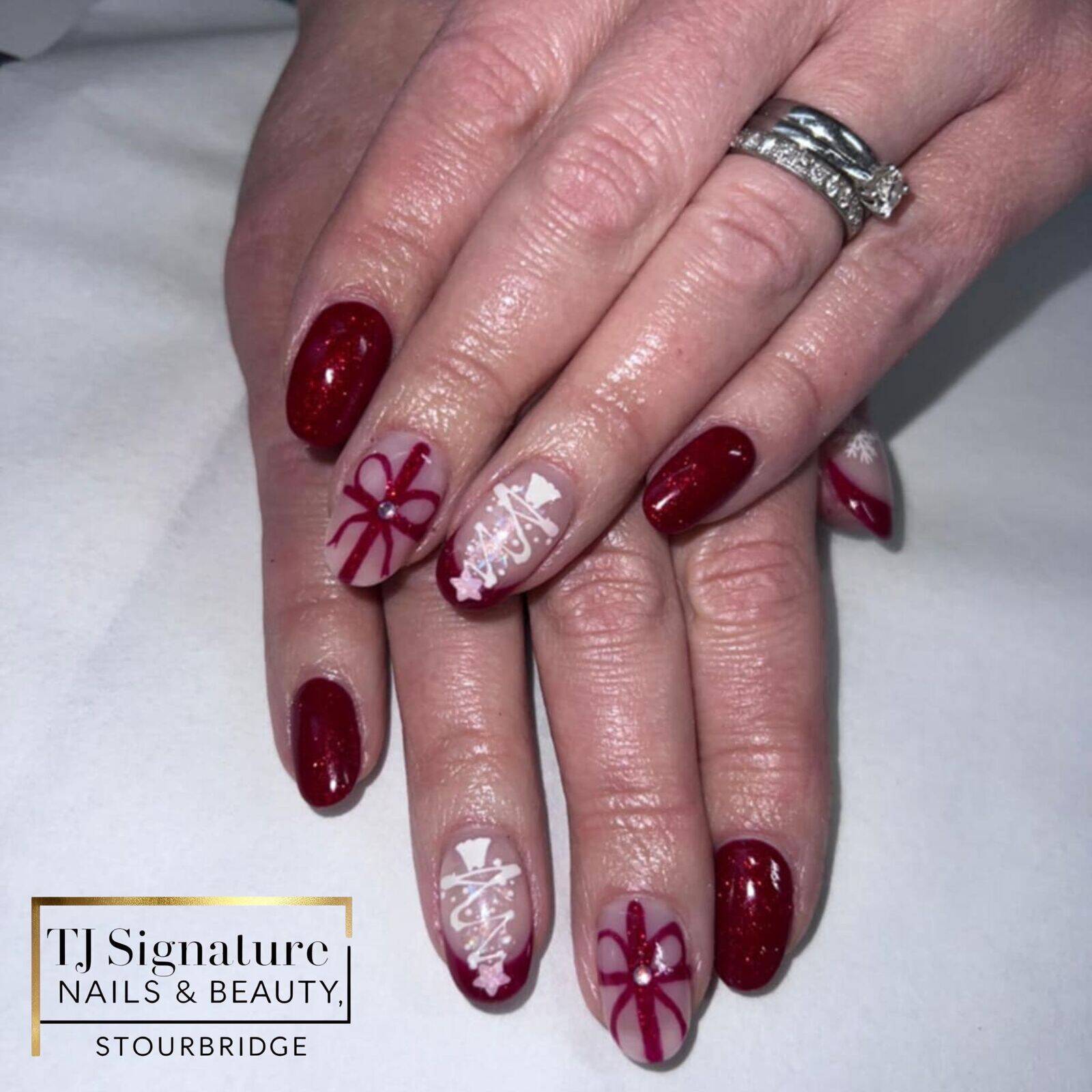 Classic festive BIAB nails with deep red tones, soft nude accents and subtle bows, Christmas trees and snowflake details for an elegant seasonal finish.