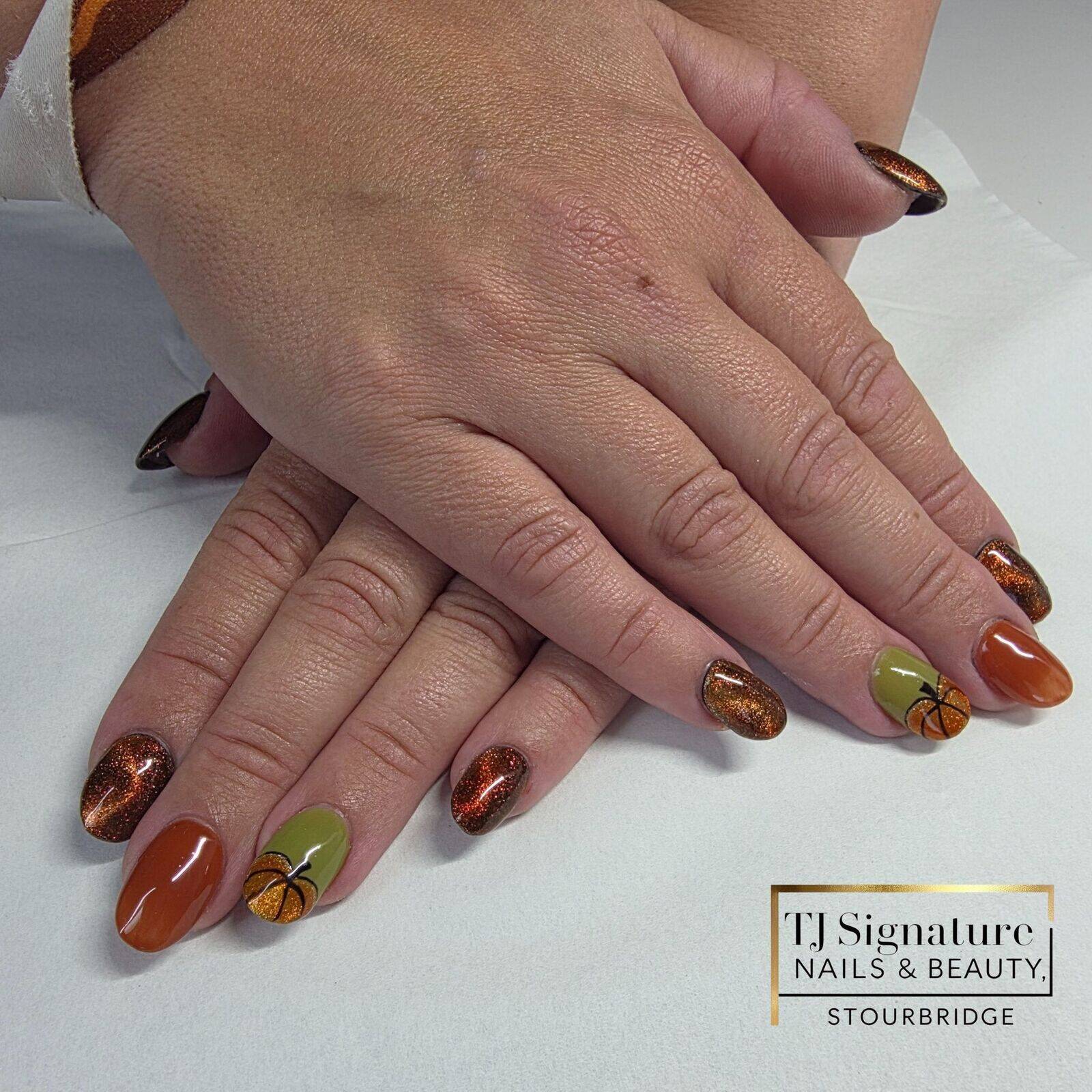Warm autumn-inspired acrylic nails featuring burnt orange and olive green tones, sparkling cat-eye shimmer, and hand-painted pumpkin accents – perfect for celebrating the season in style.